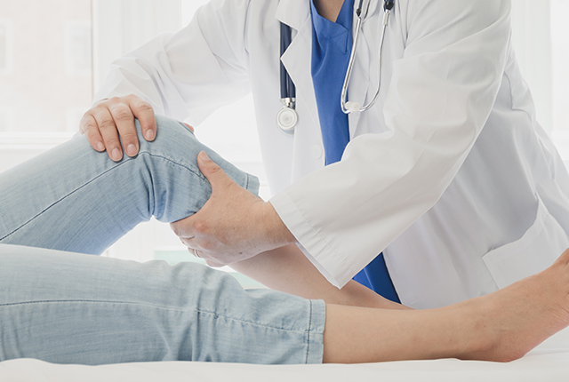 両手で膝を診察する医師